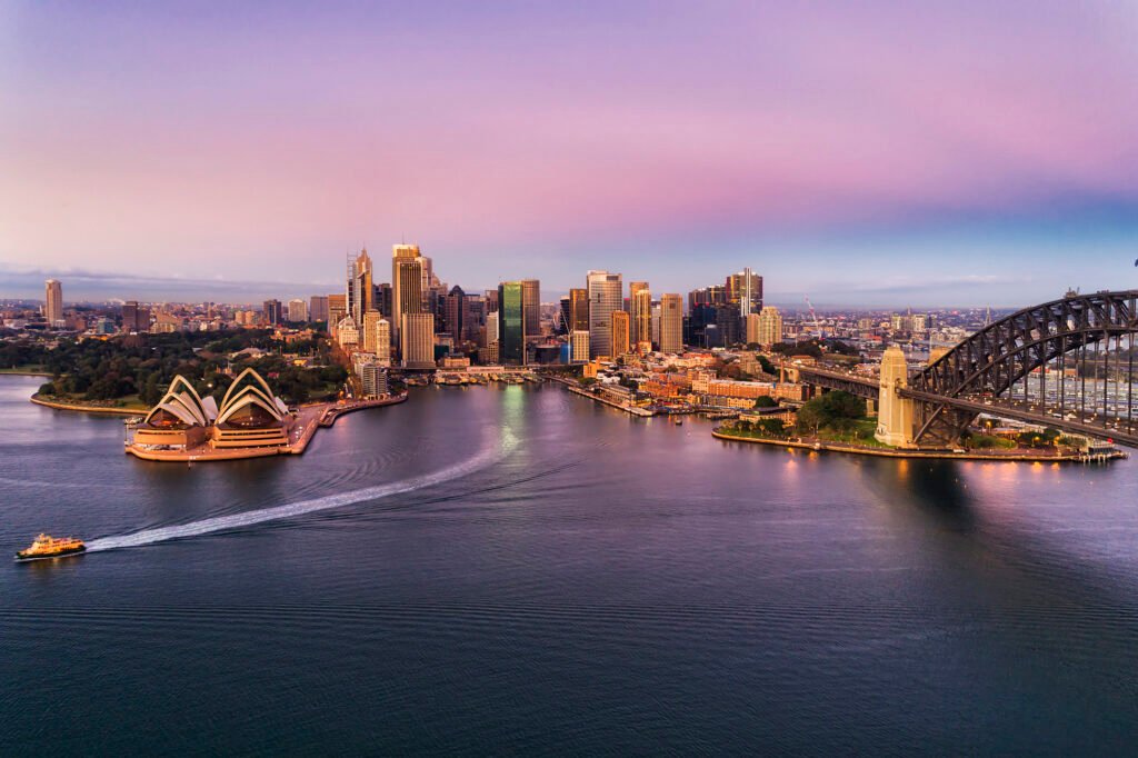 Aerial shot of Sydney Harbour against a pink sunset